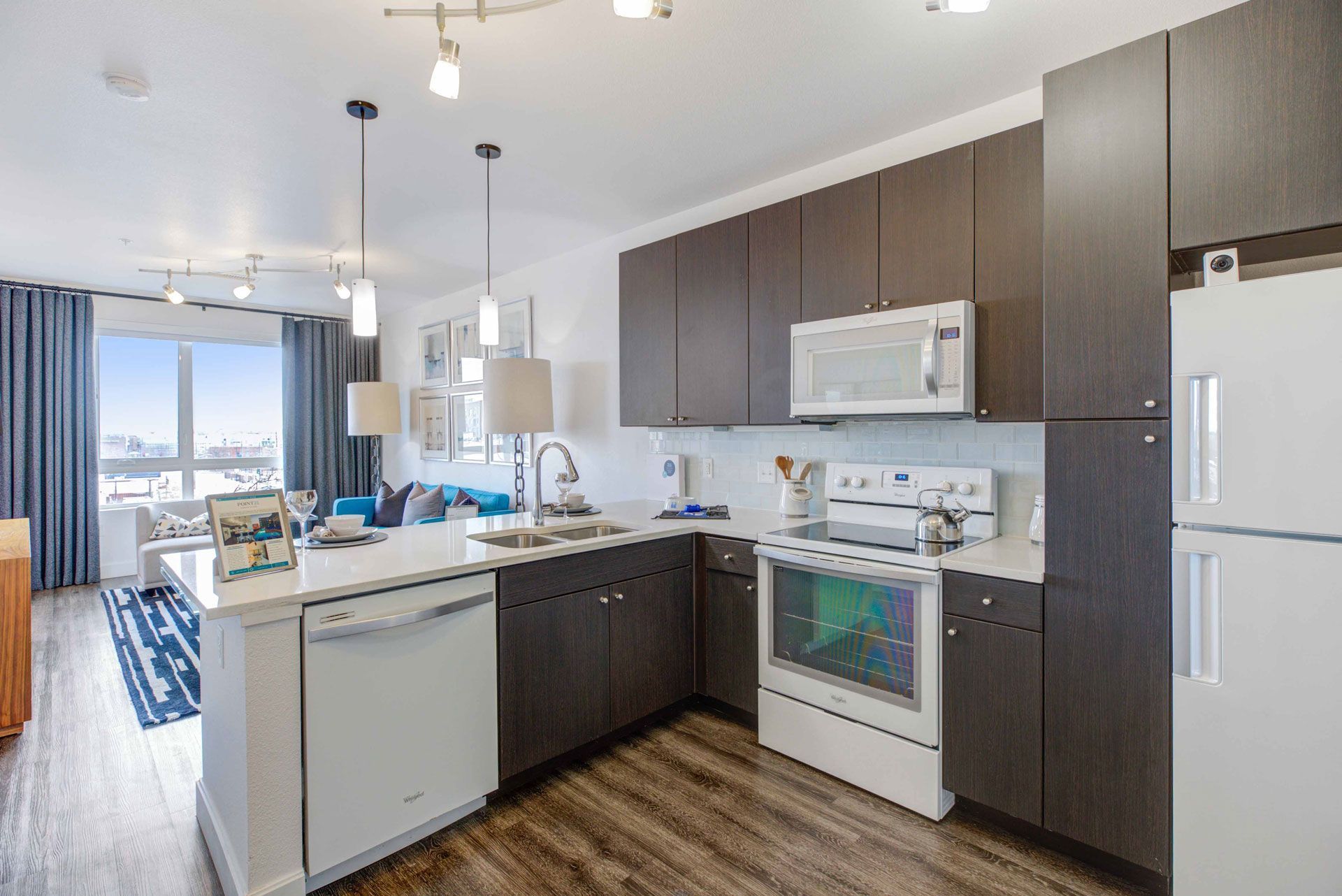 Modern kitchen with dark brown cabinets, white countertops, and stainless steel appliances.