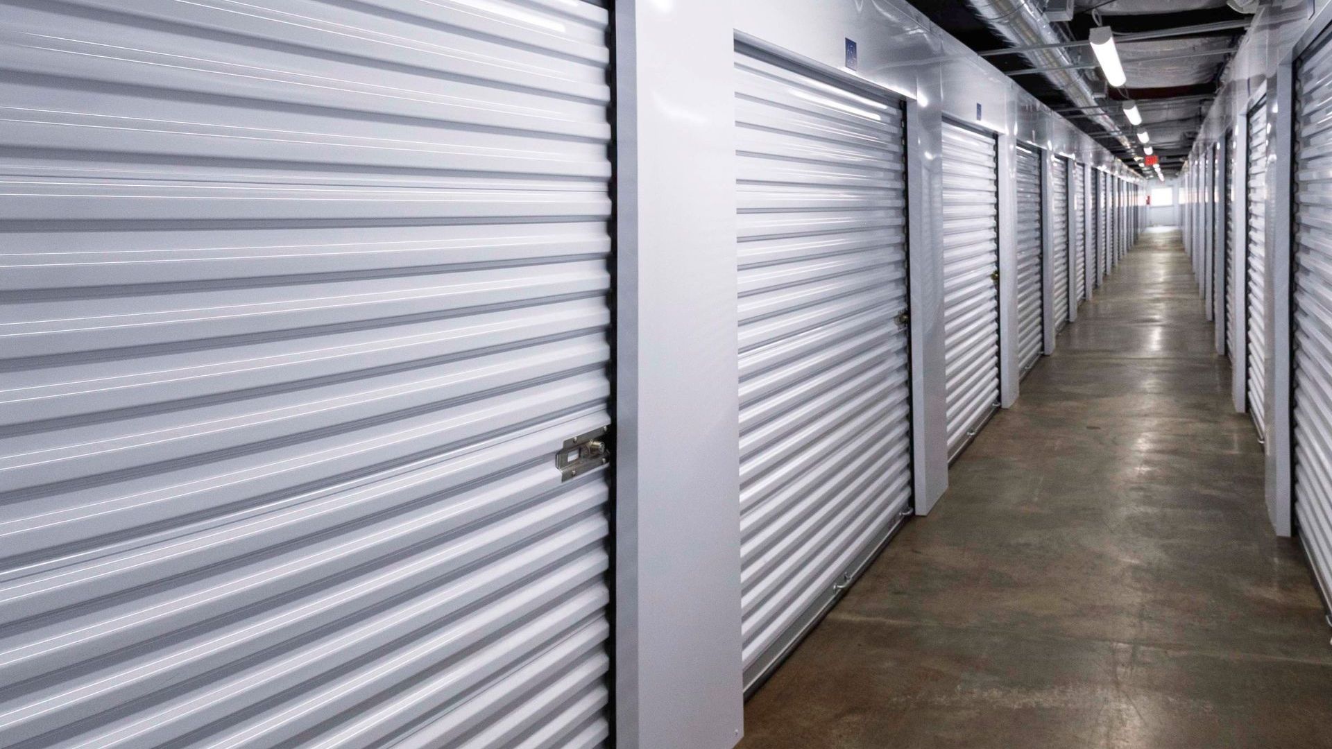 A climate controlled self-storage hallway with clean floors and white doors in Burling