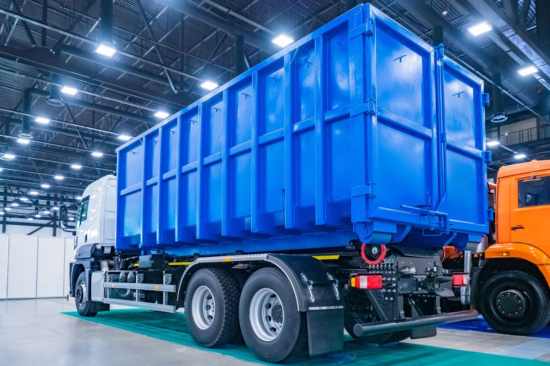 Blue cargo trailer in a warehouse, attached to an orange truck cab Blue cargo trailer in a warehouse, attached to an orange truck cab