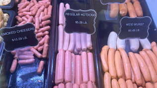 Display case with different sausages: smoked cheddar, regular hotdogs, and bratwurst.