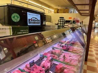 Meat counter at Aaron's Fresh Meats, showcasing various cuts of fresh meat under bright lights.