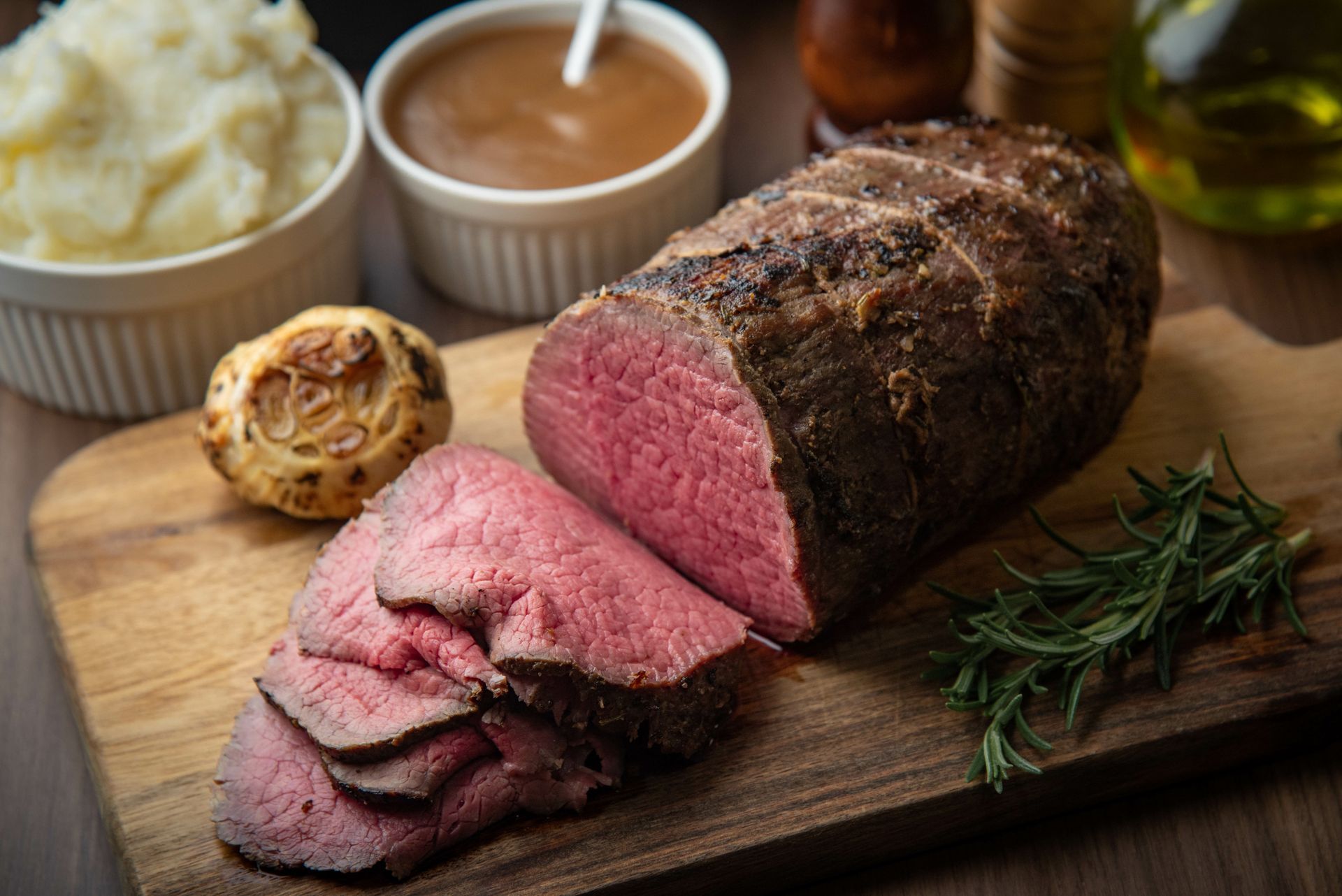 Sliced roast beef, Yorkshire pudding, mashed potatoes, and gravy on a wooden board. Sliced roast beef, Yorkshire pudding, mashed potatoes, and gravy on a wooden board.