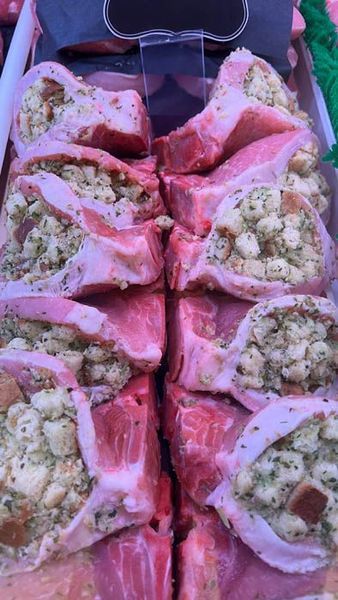 Stuffed pork chops in a display case; pink meat with bread stuffing, lit from above.