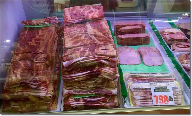 Meat display case with bacon and other sliced pork products.