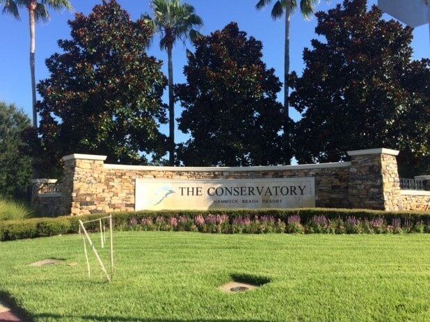 A sign for the conservatory is in the middle of a lush green field.