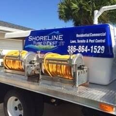 A shoreline turf and pest truck is parked in front of a house.