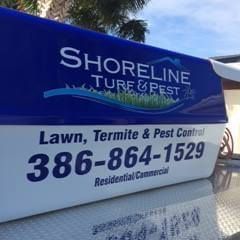 A blue and white sign for shoreline turf and pest lawn , termite and pest control.
