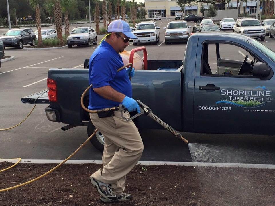 A man spraying a shoreline truck with a sprayer