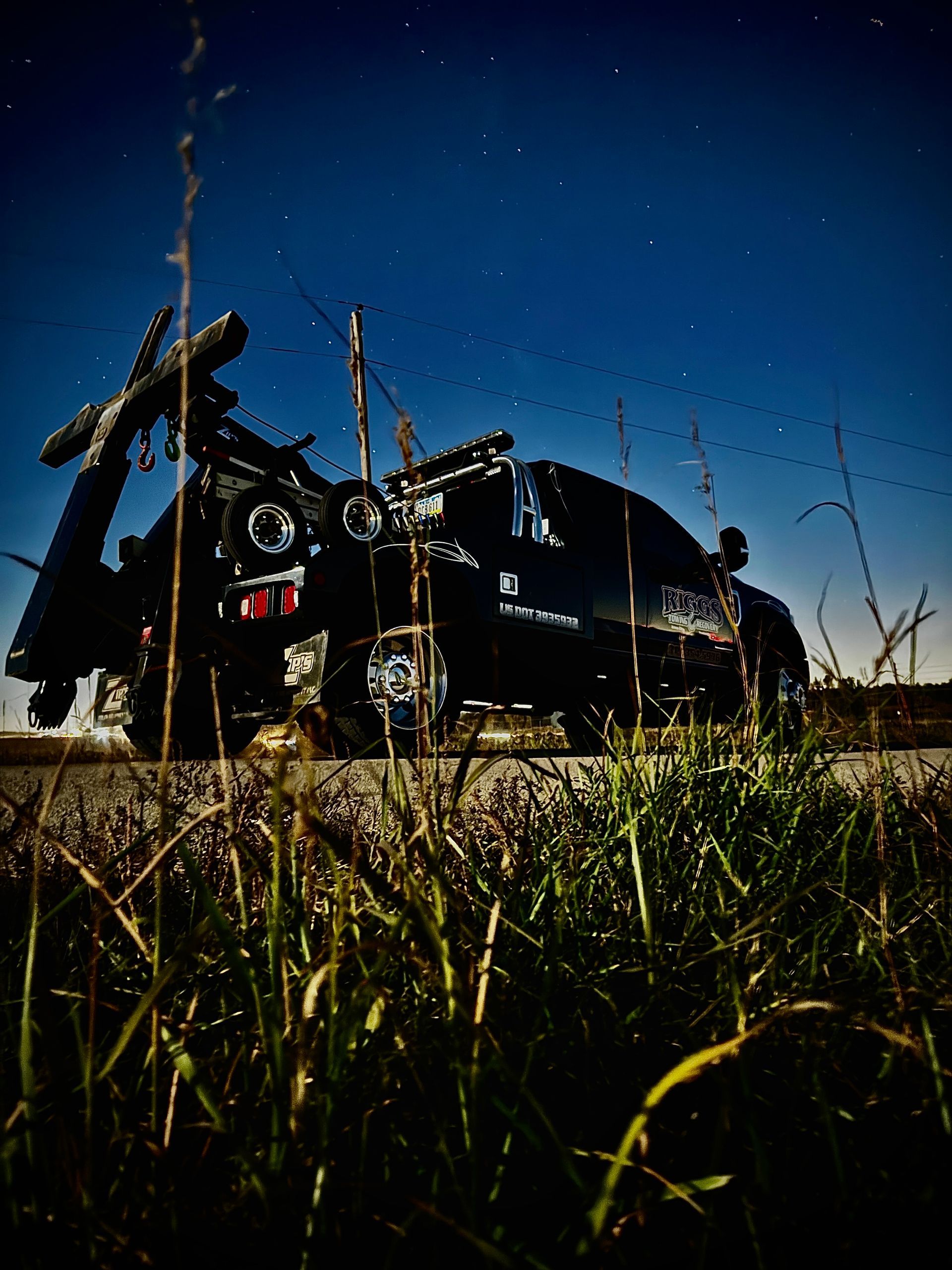 A black tow truck is parked on the side of the road