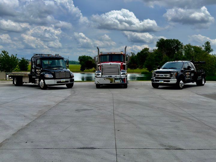 Three tow trucks are parked in a parking lot