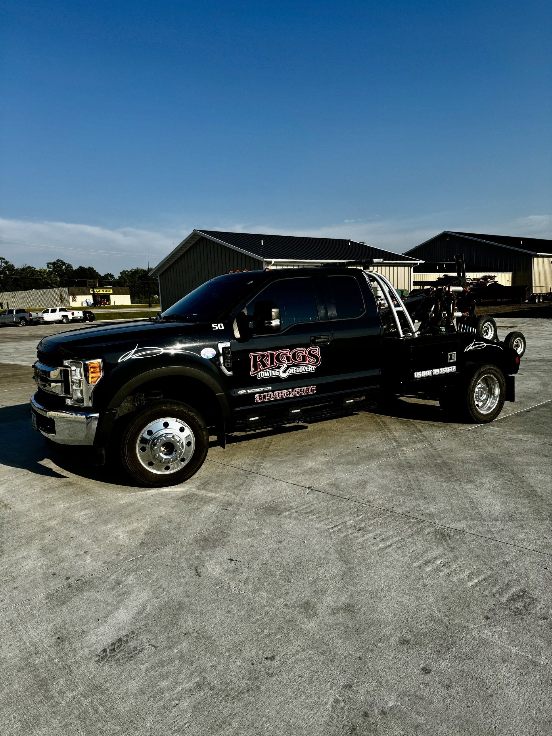 A black tow truck is parked in a parking lot.