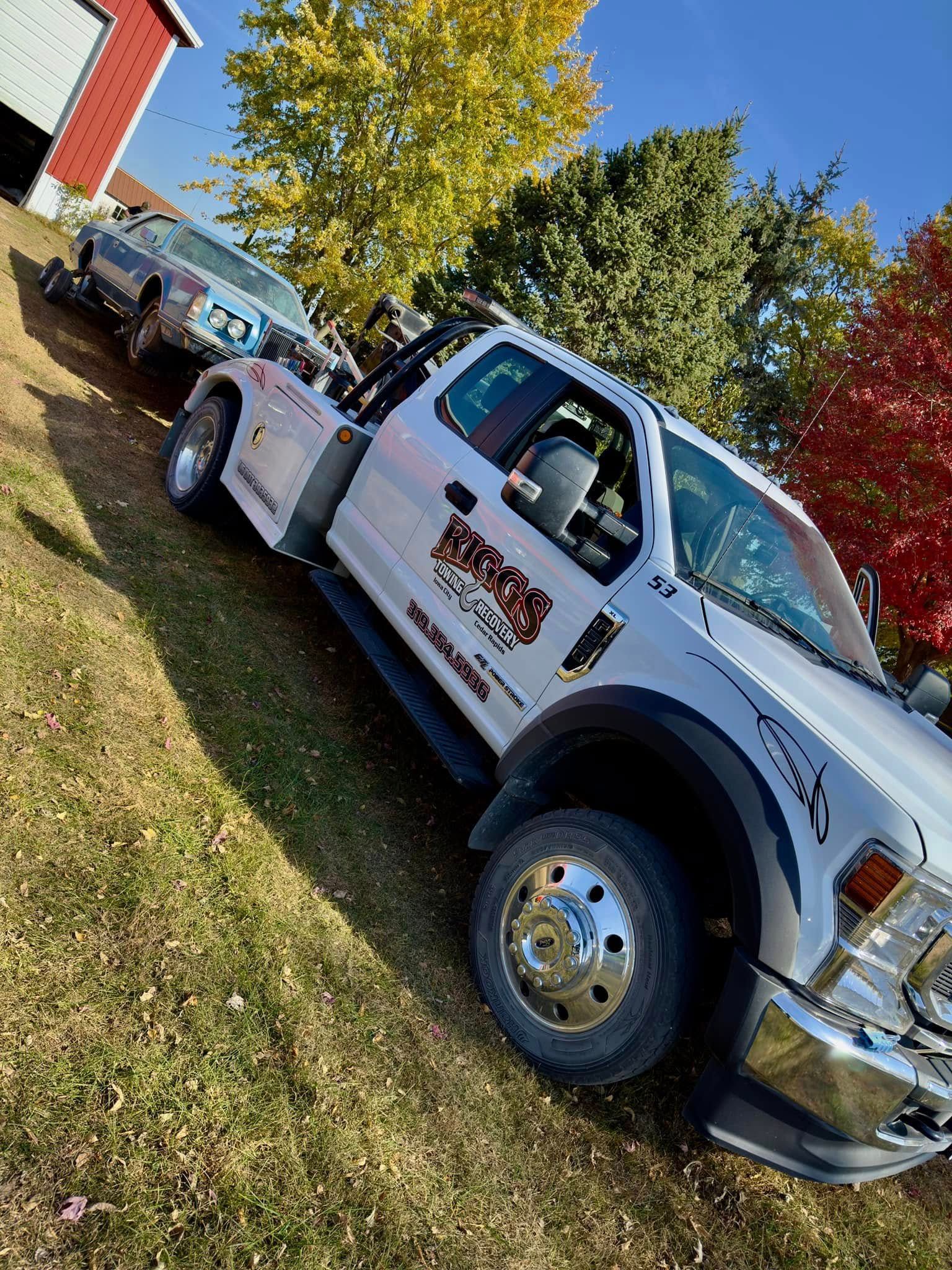 A white tow truck is parked in a grassy field.