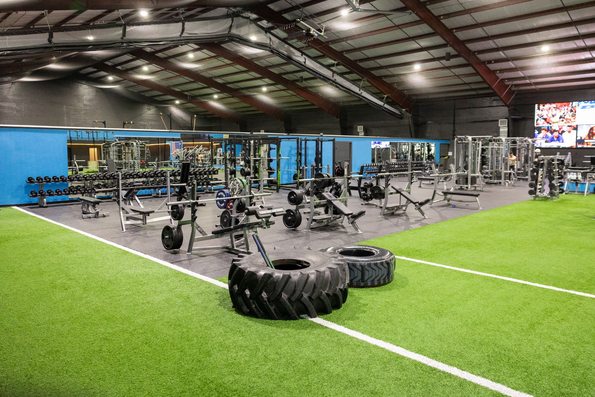 Wide view of the Freedom Fitness gym featuring cardio equipment, weight machines, free weights, and turf space.