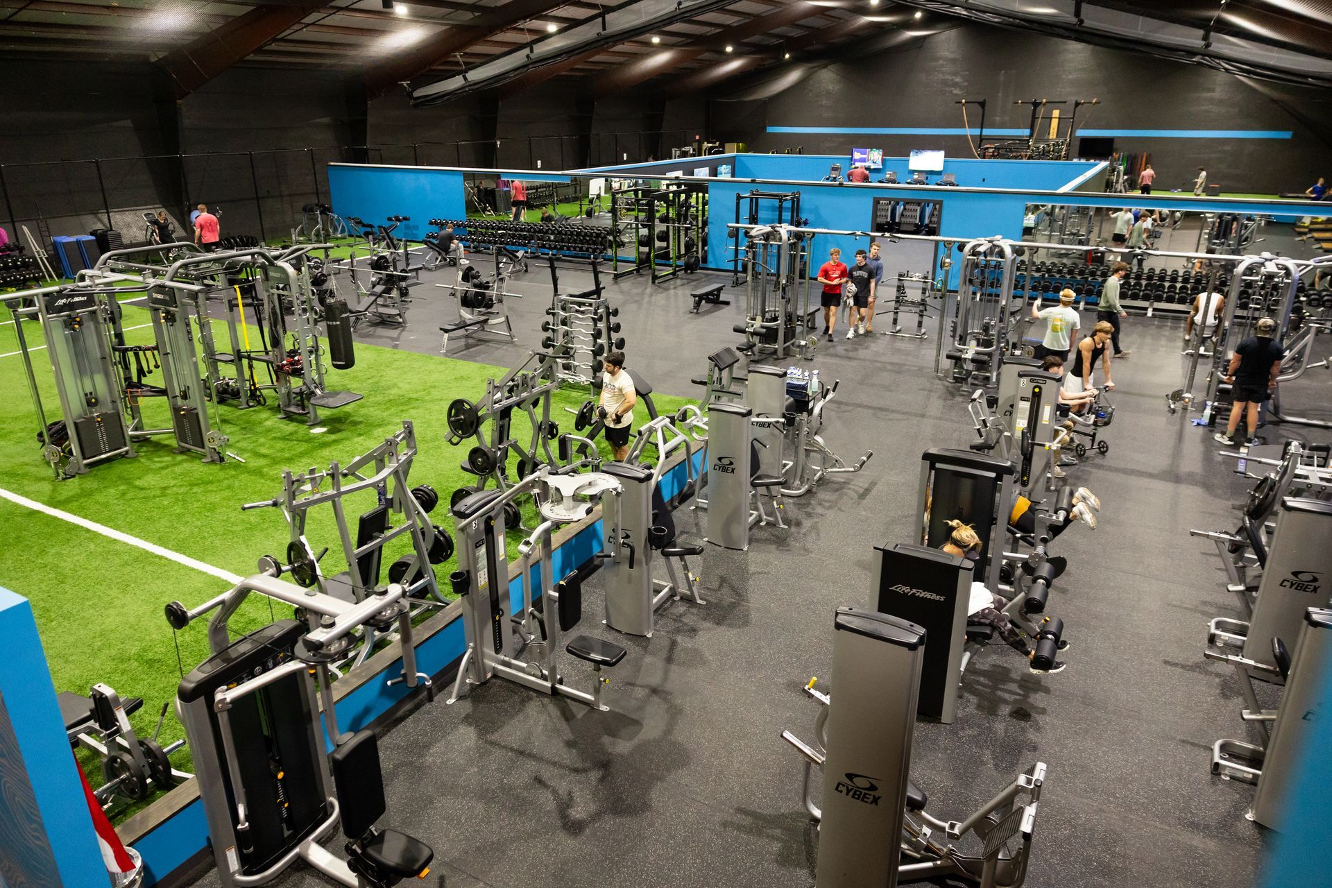 Wide view of the Freedom Fitness gym featuring cardio equipment, weight machines, free weights, and turf space.