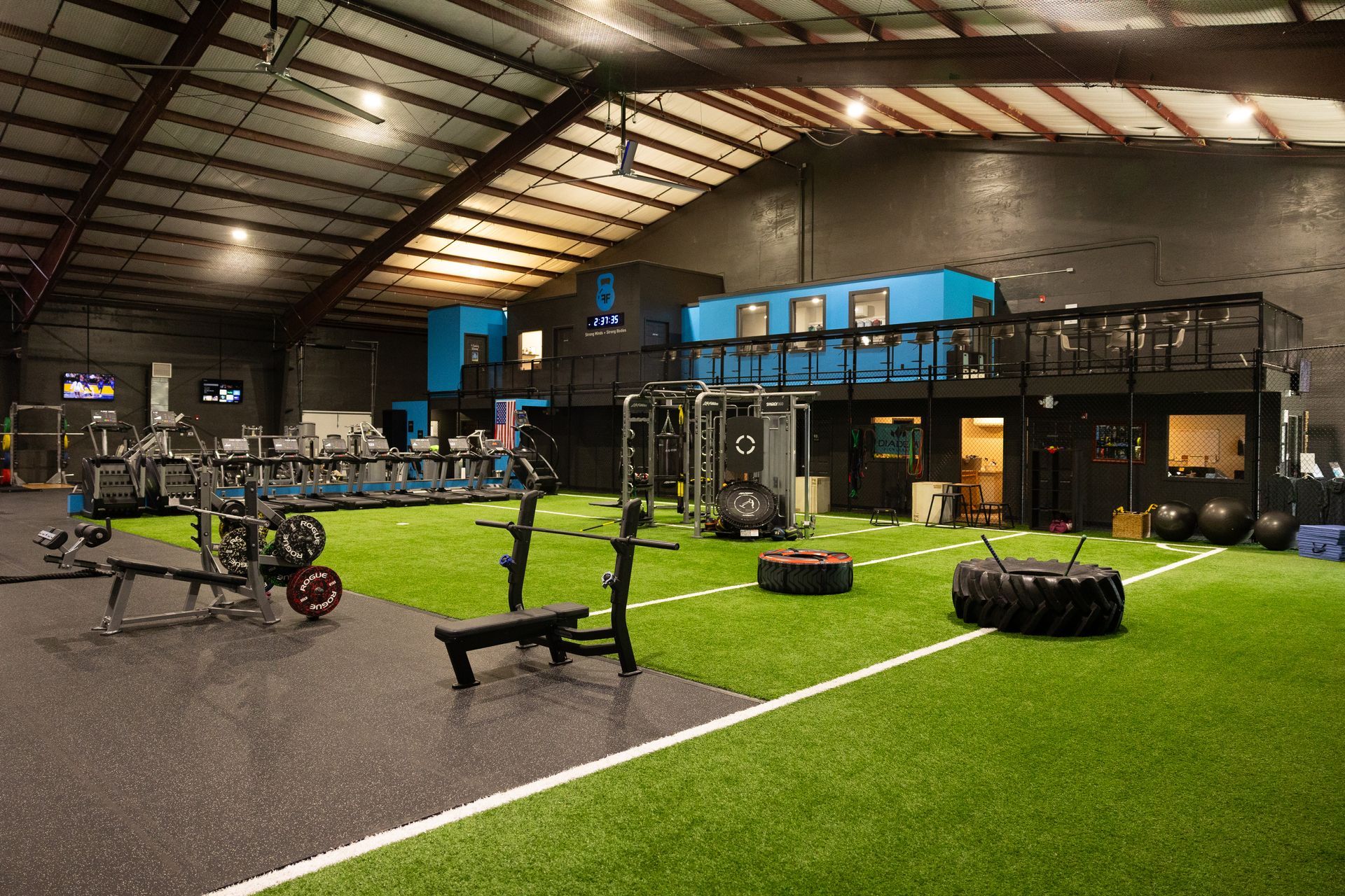 Freedom Fitness indoor turf training area with strength equipment, cardio machines, and functional fitness setup.