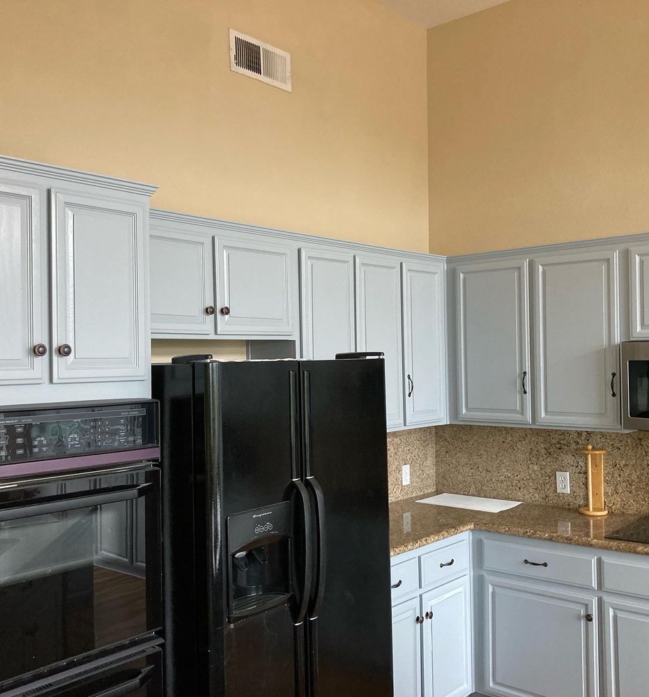 A kitchen with white cabinets and a black refrigerator