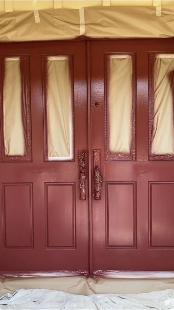 A pair of red doors are covered in plastic.