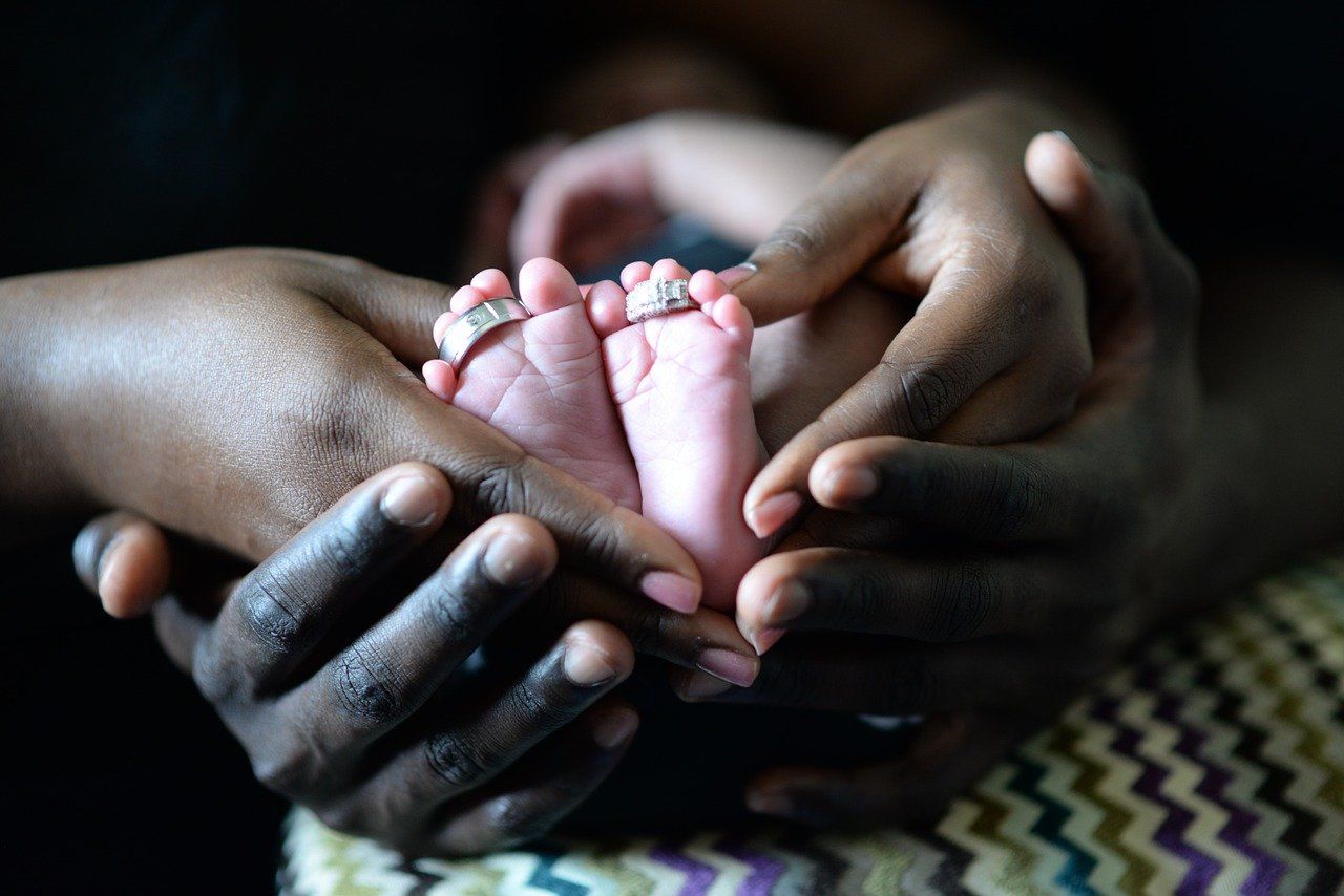 A person is holding a baby 's foot with a ring on it