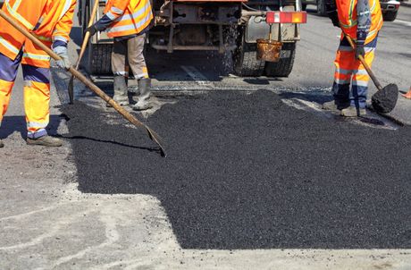 workers are putting asphalt on the driveway