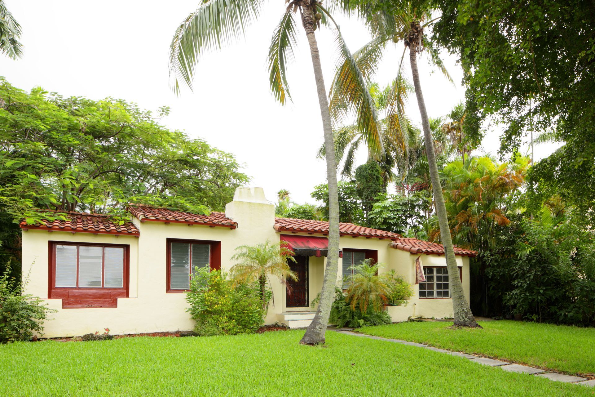 A single-family home with palm trees in the front green lawn.