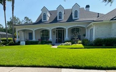 A large white house with a lush green lawn in front of it. A large white house with a lush green lawn in front of it.