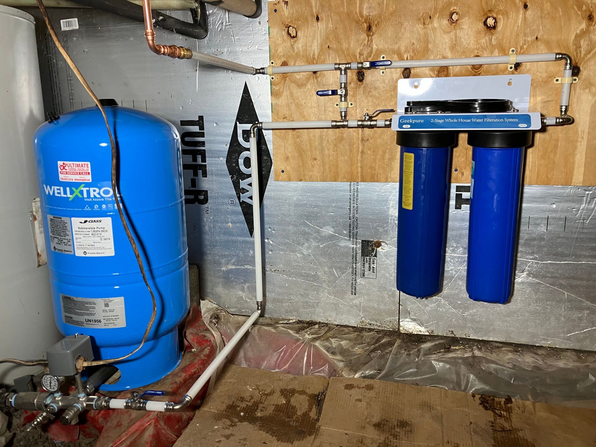 Blue water pressure tank and filter system against a wooden wall.