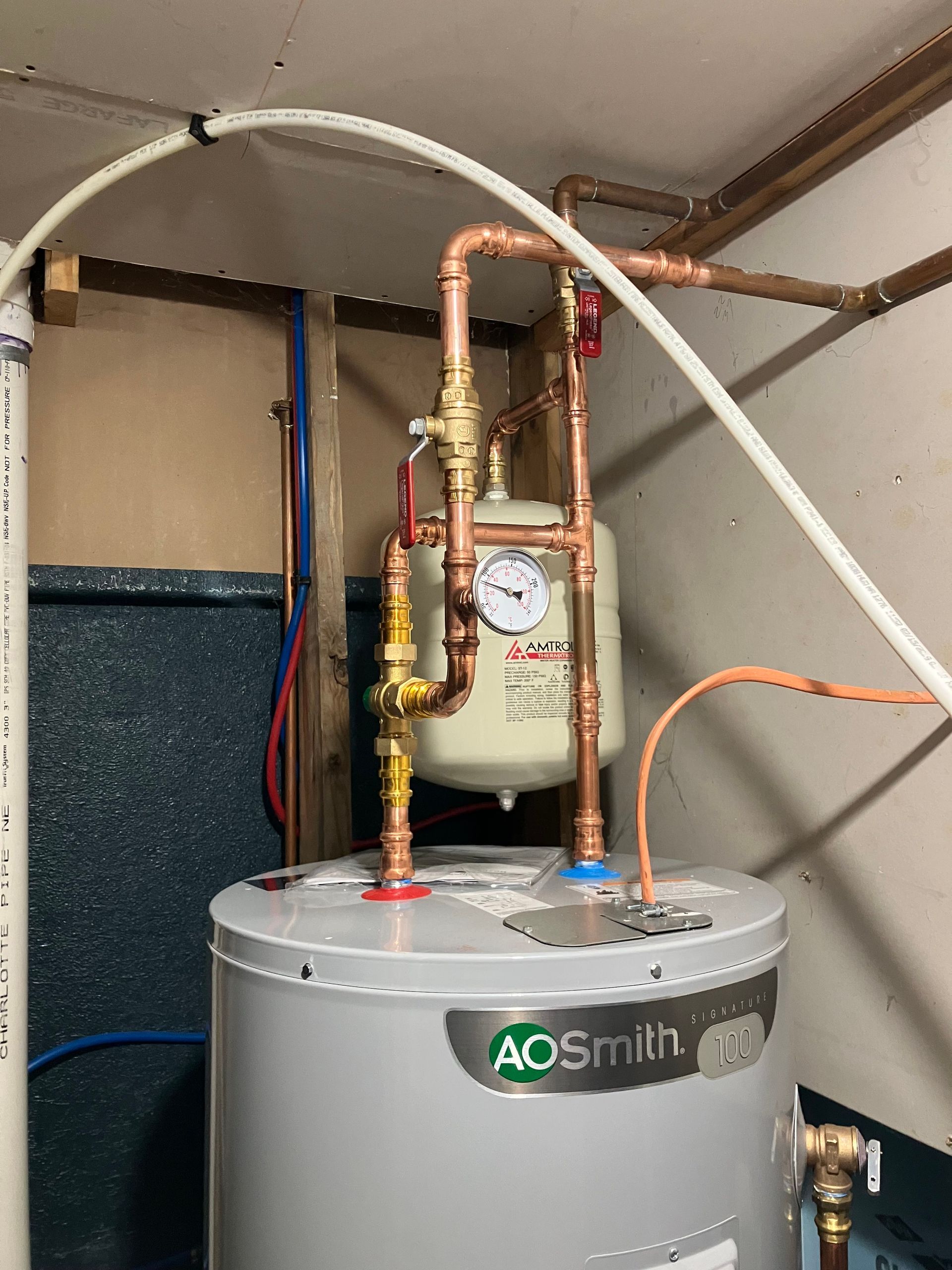 A.O. Smith water heater with copper pipes, expansion tank, and pressure gauge in a basement.