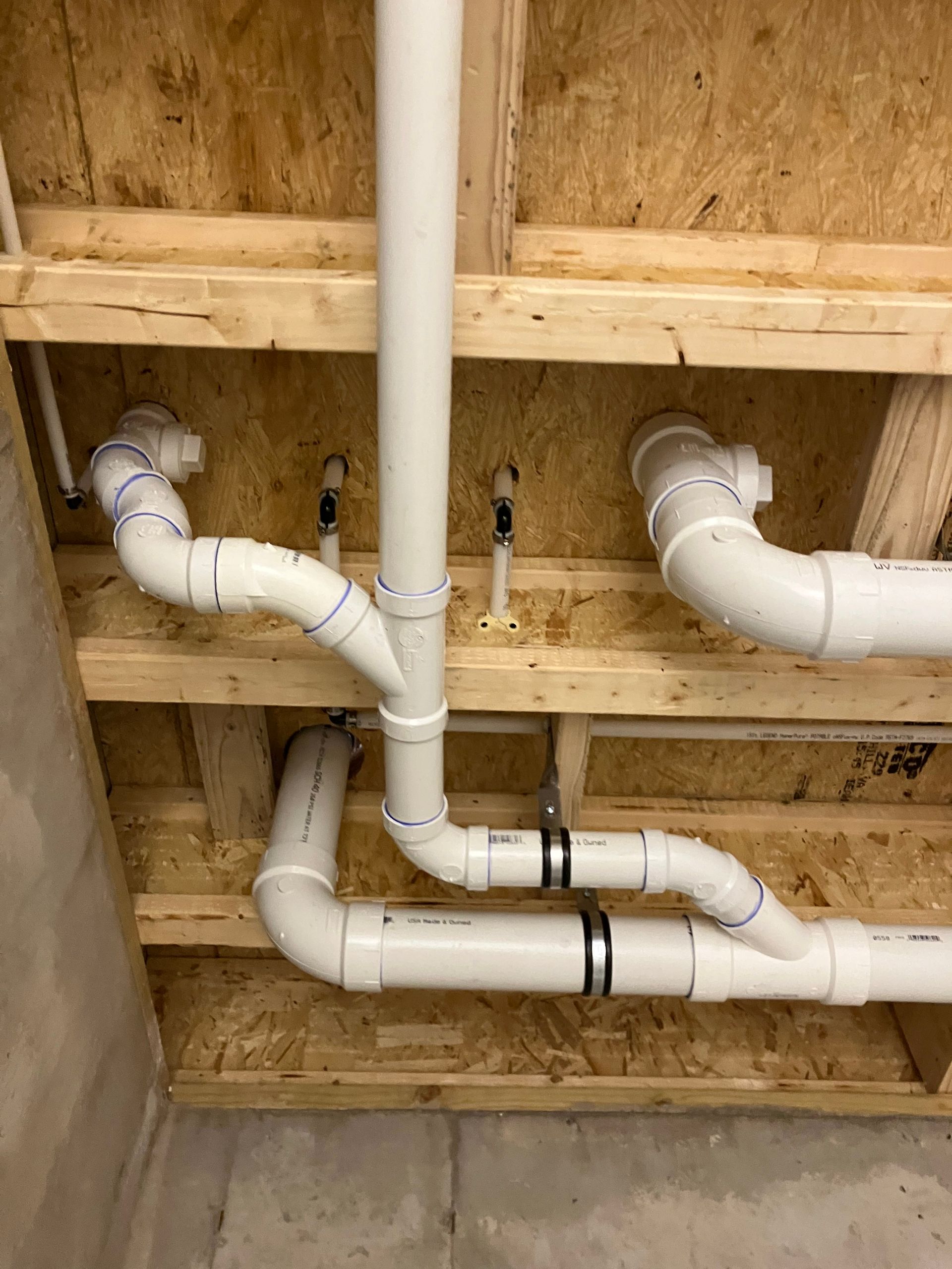 Plumbing pipes in a wooden ceiling, white PVC pipes with fittings, set in a basement.