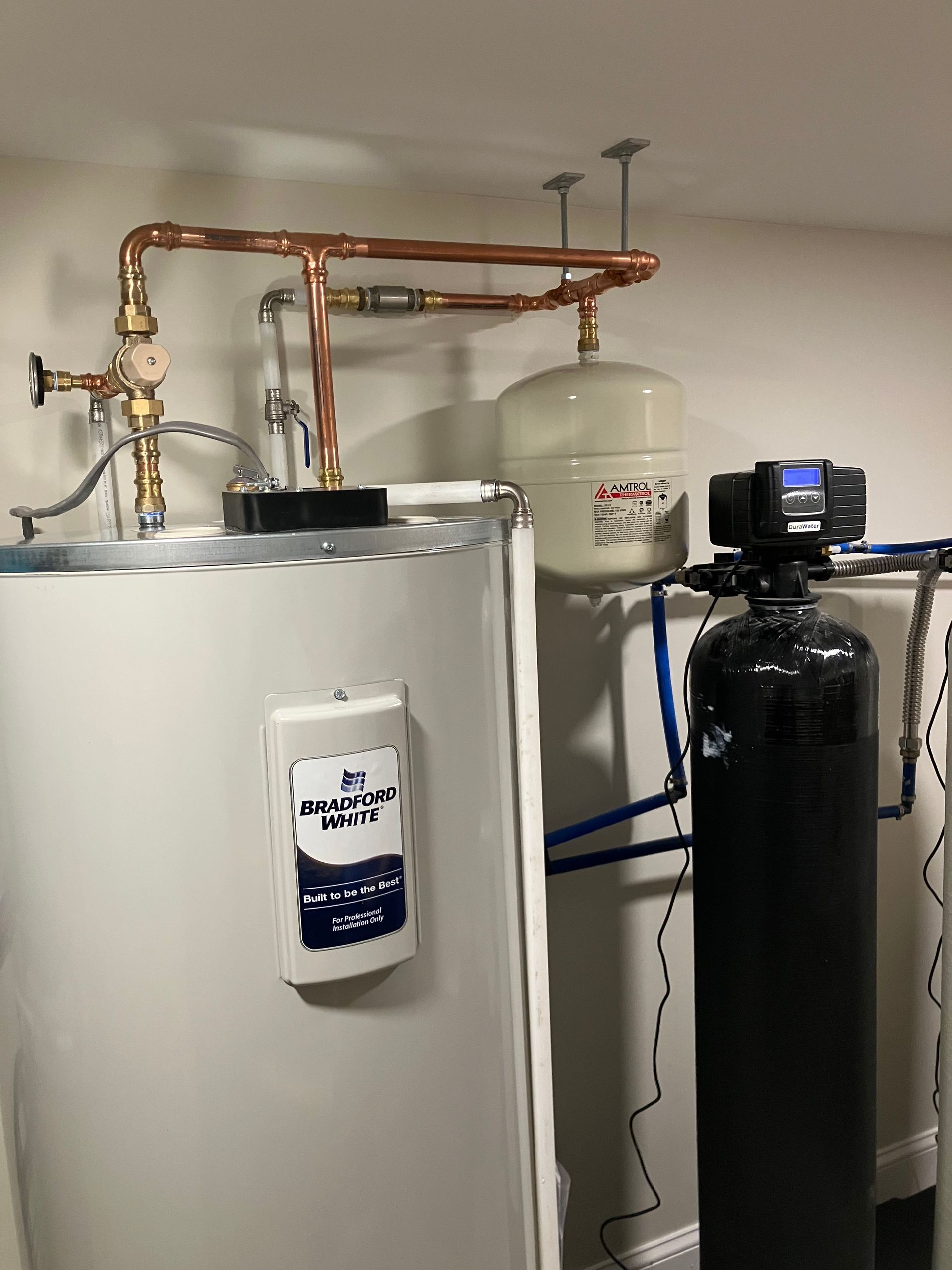Water heater, copper pipes, expansion tank, and water softener in a basement.