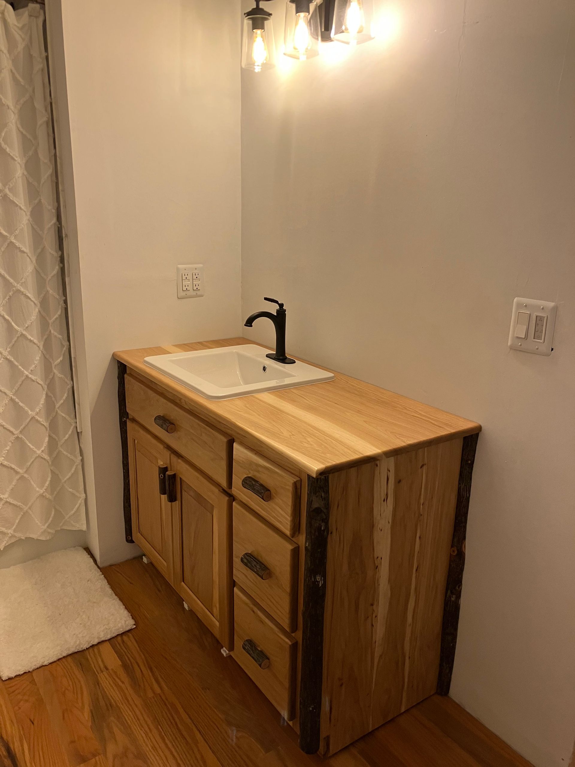 Bathroom vanity with a wooden countertop, a white sink, and black faucet.