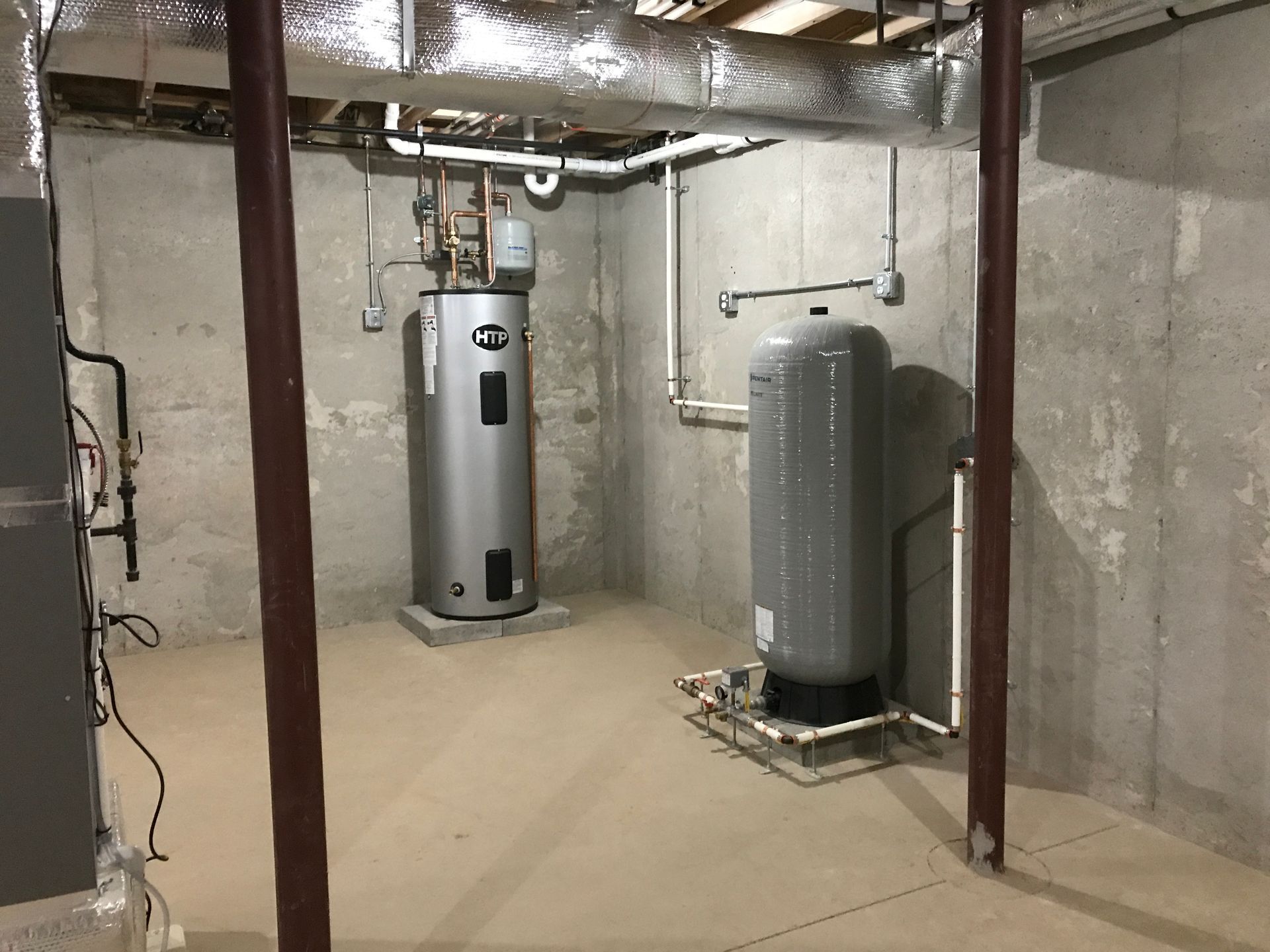 Basement with a water heater and pressure tank, concrete walls, and support beams.