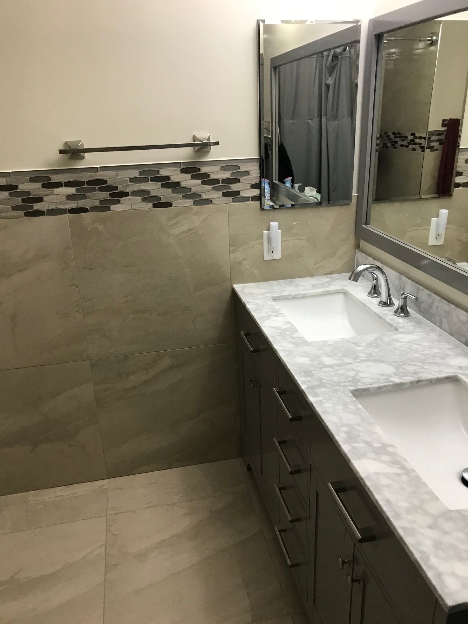 Bathroom with double sink vanity, marble countertop, large mirror, and gray tile.
