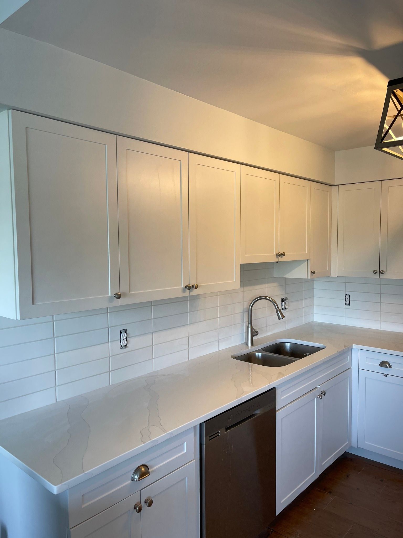 White kitchen with cabinets, countertops, and stainless steel sink and dishwasher.