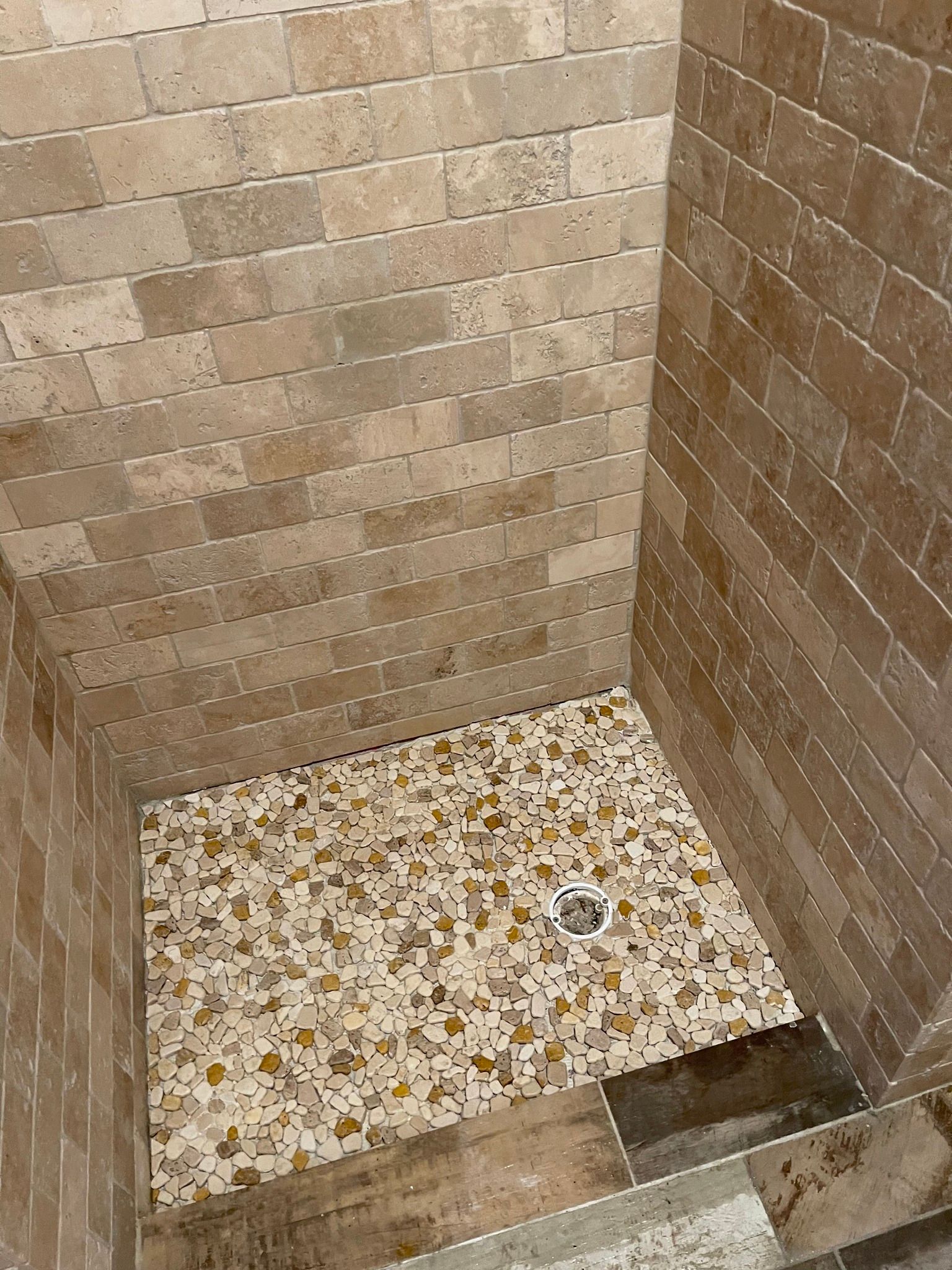 Shower stall with tiled walls and floor featuring a colorful mosaic.