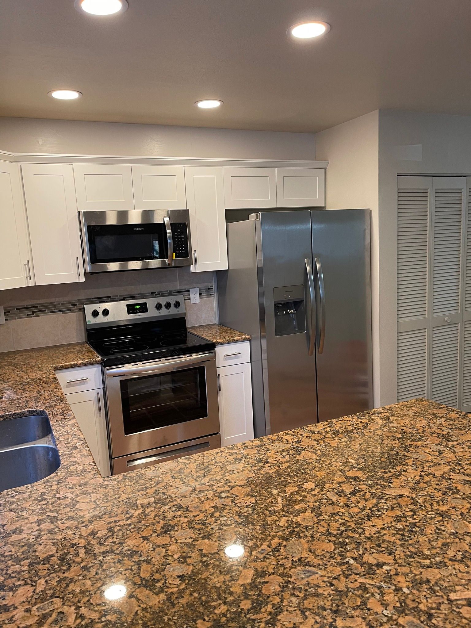 Kitchen with white cabinets, stainless steel appliances, and a granite countertop.