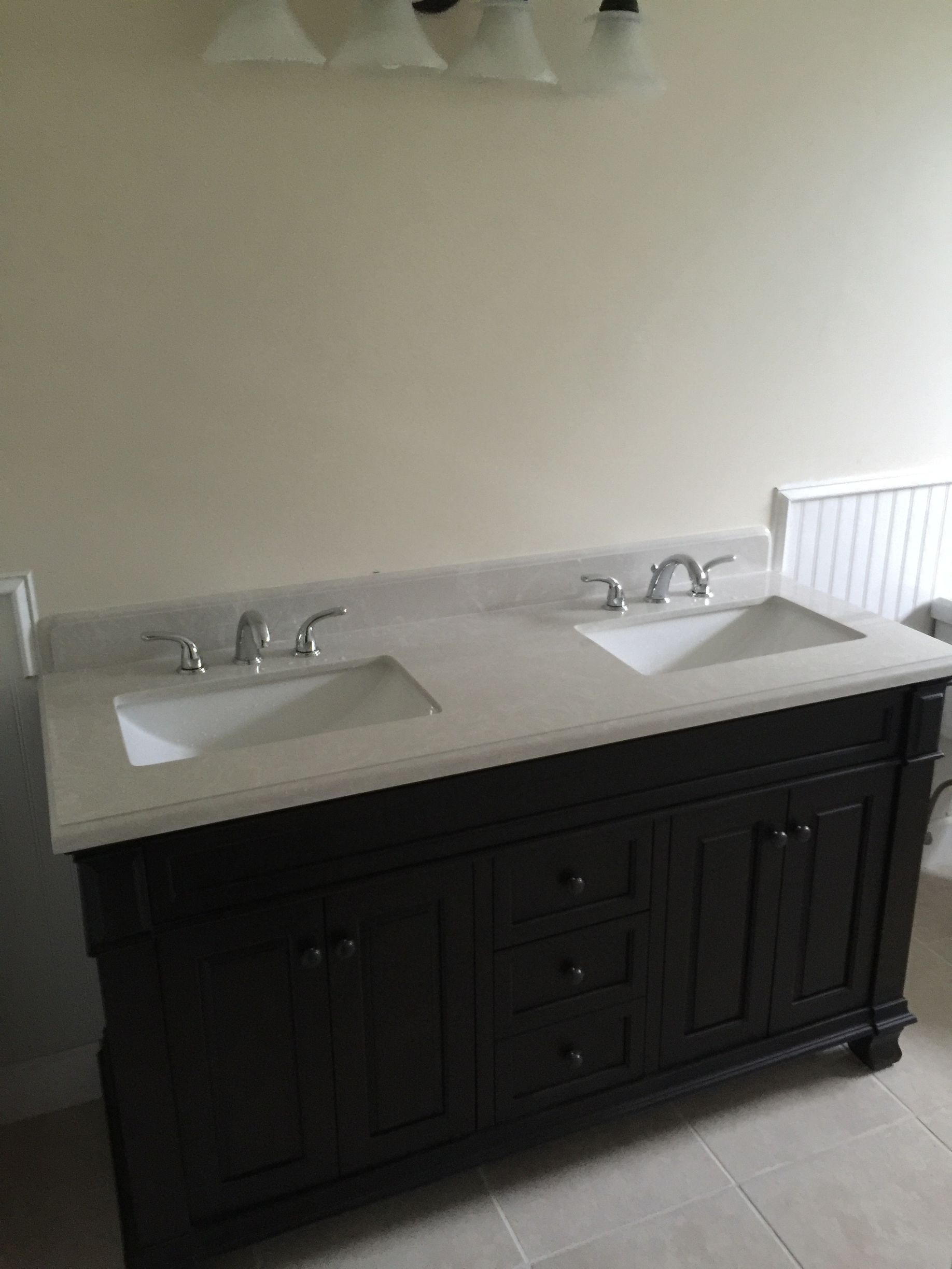 Double sink vanity with dark cabinet, light countertop, and chrome faucets in a bathroom.