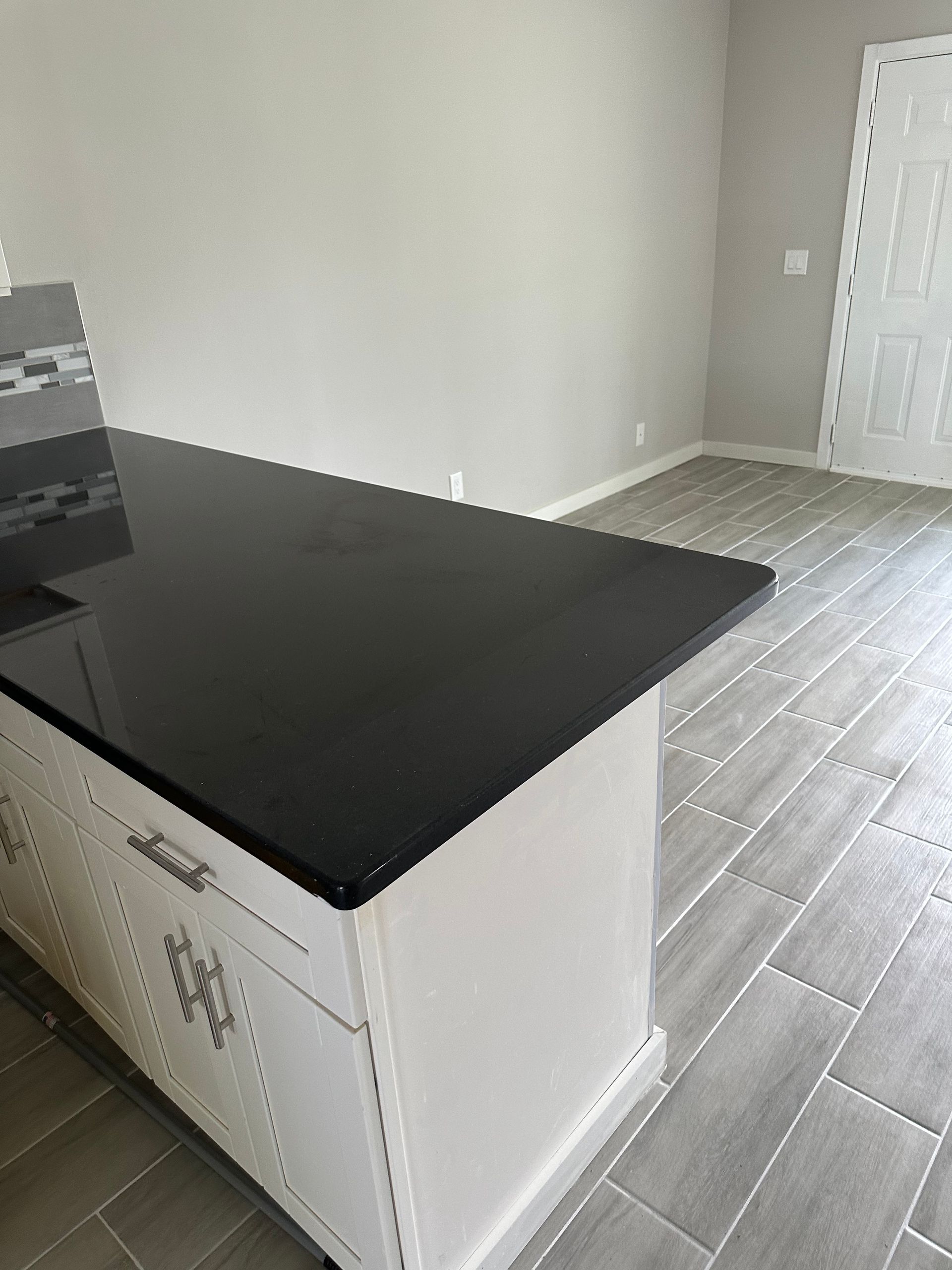 White kitchen island with black countertop; light gray walls and floor.