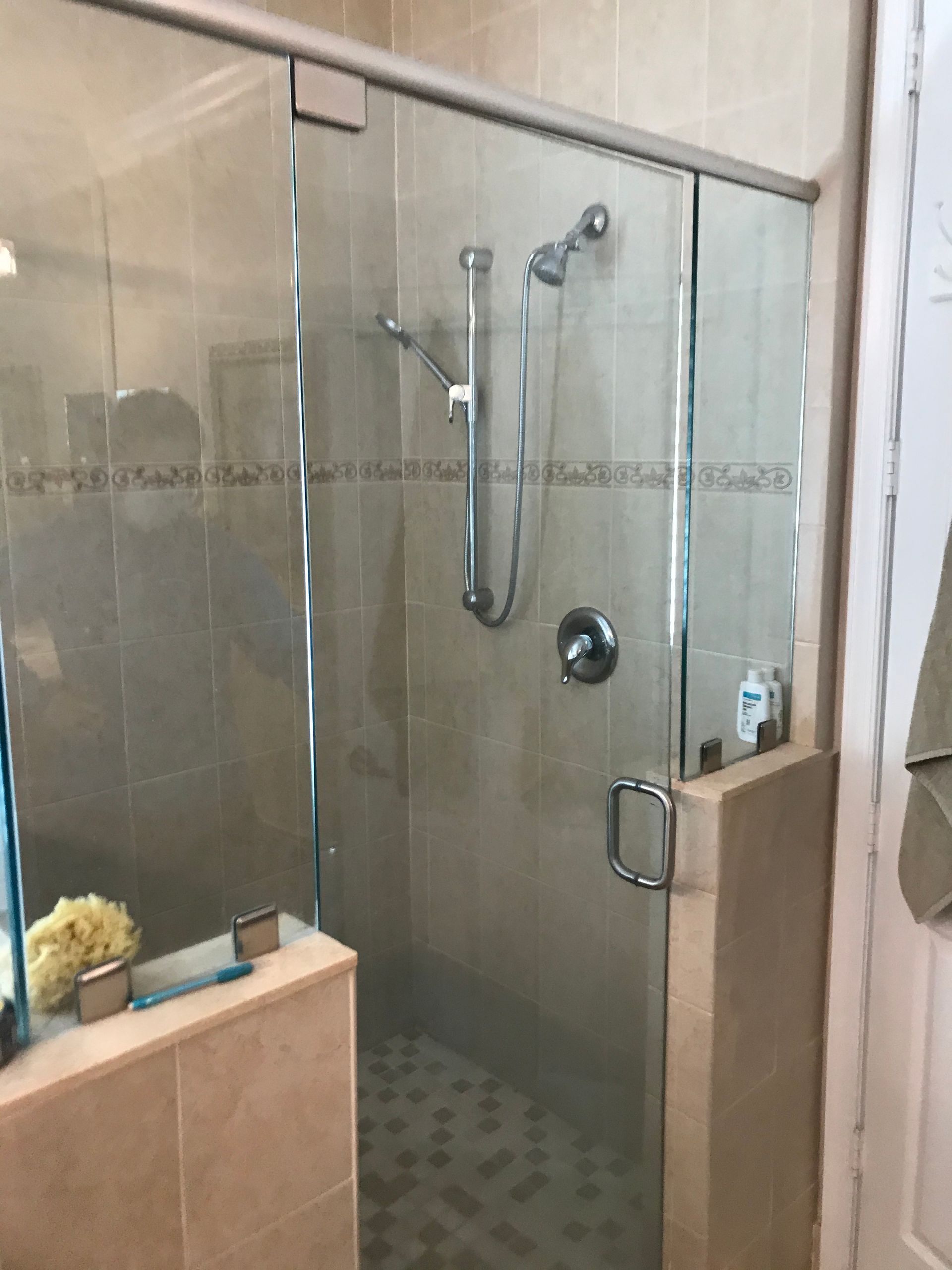 Shower with glass doors, tiled walls, and chrome fixtures in a bathroom.