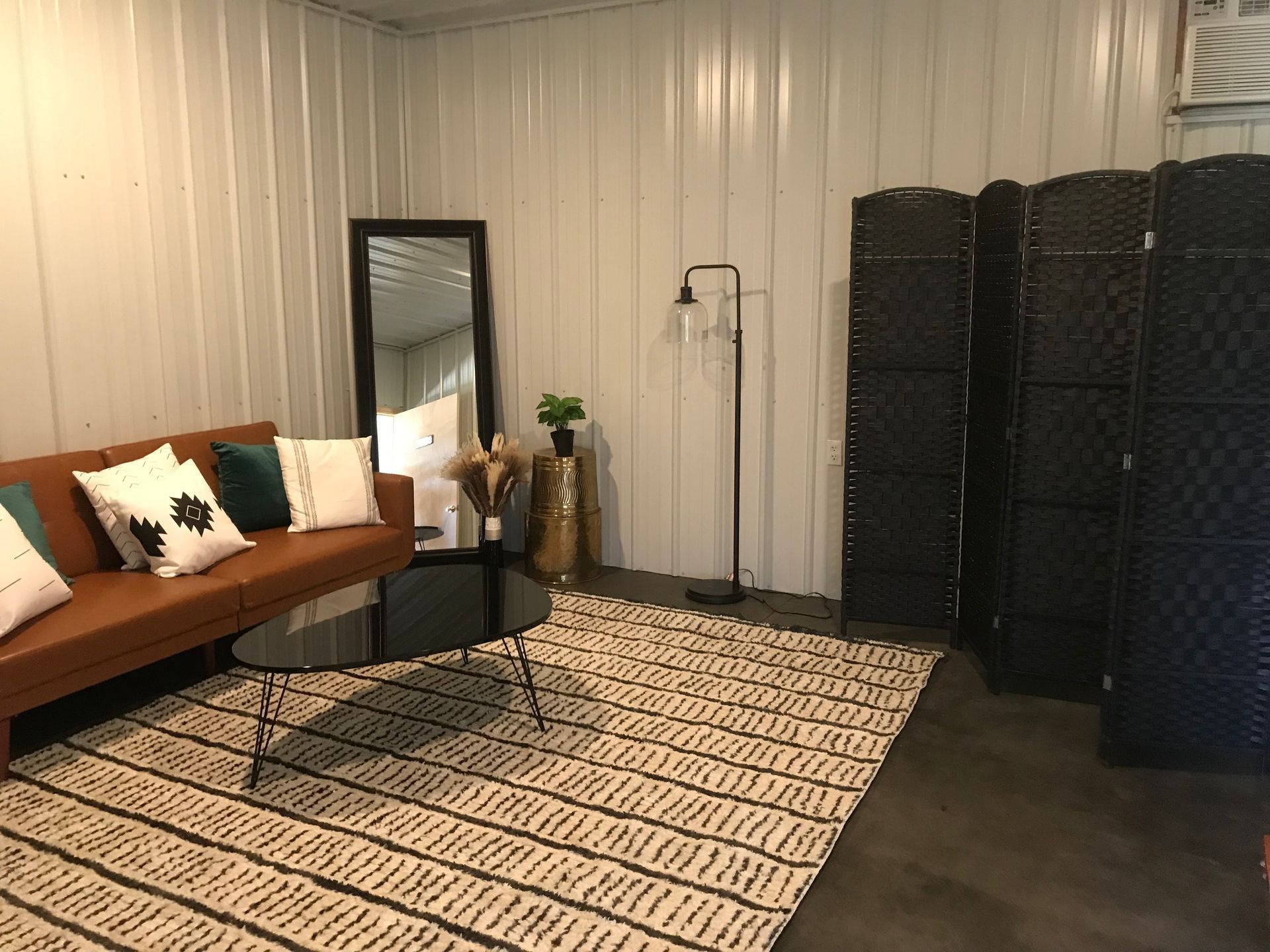 A living room with a couch , table , mirror and rug.