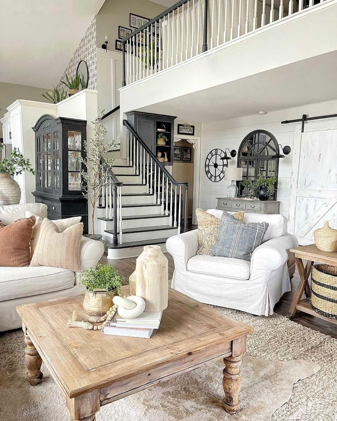 A living room with a coffee table , chairs , and stairs.