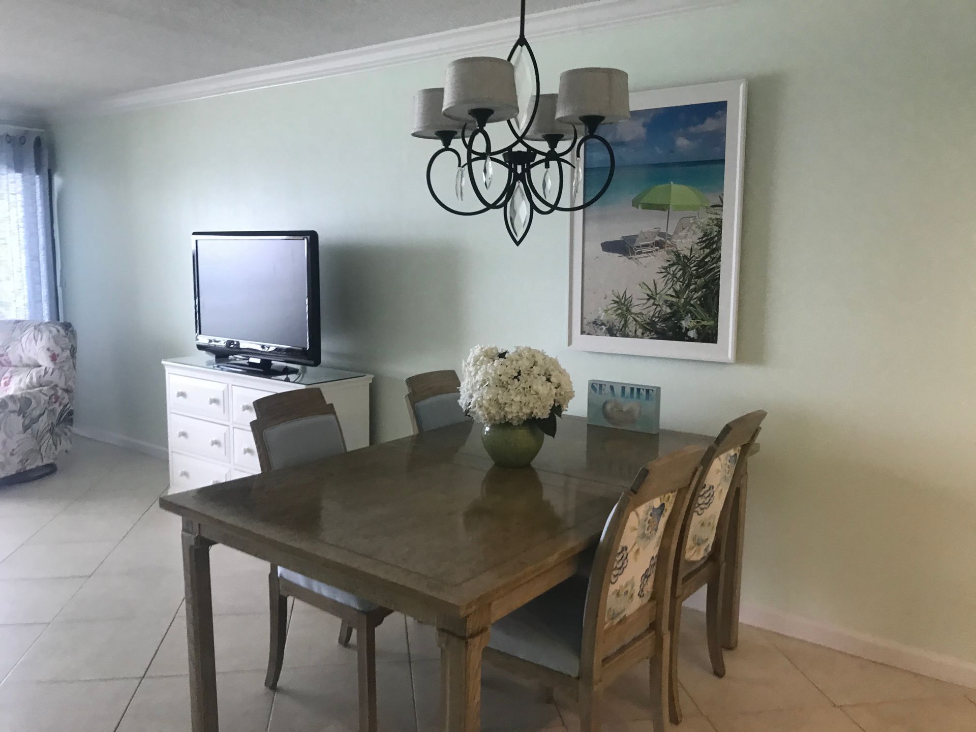 A dining room with a table and chairs and a television