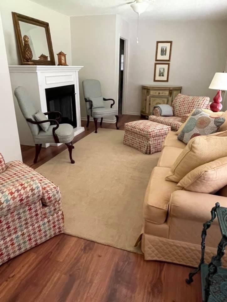 A living room with a couch , chairs , ottoman and fireplace.