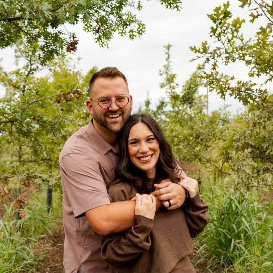 A man and a woman are posing for a picture in a field.