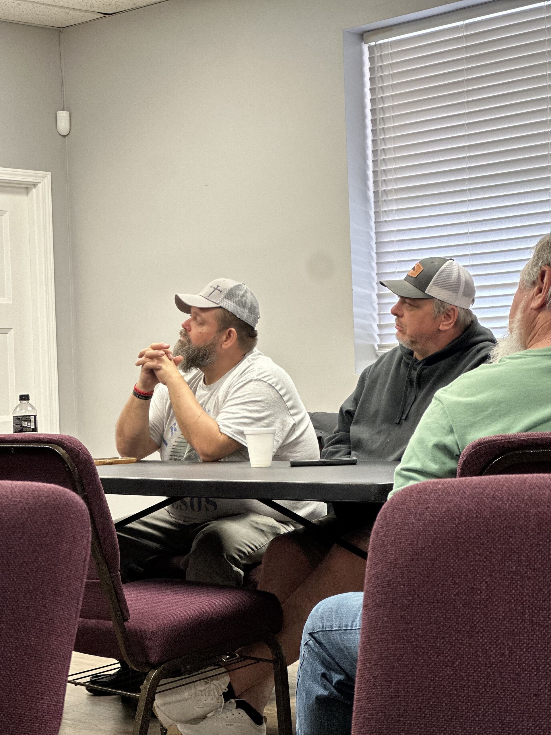 A group of men are sitting at a table in a room.