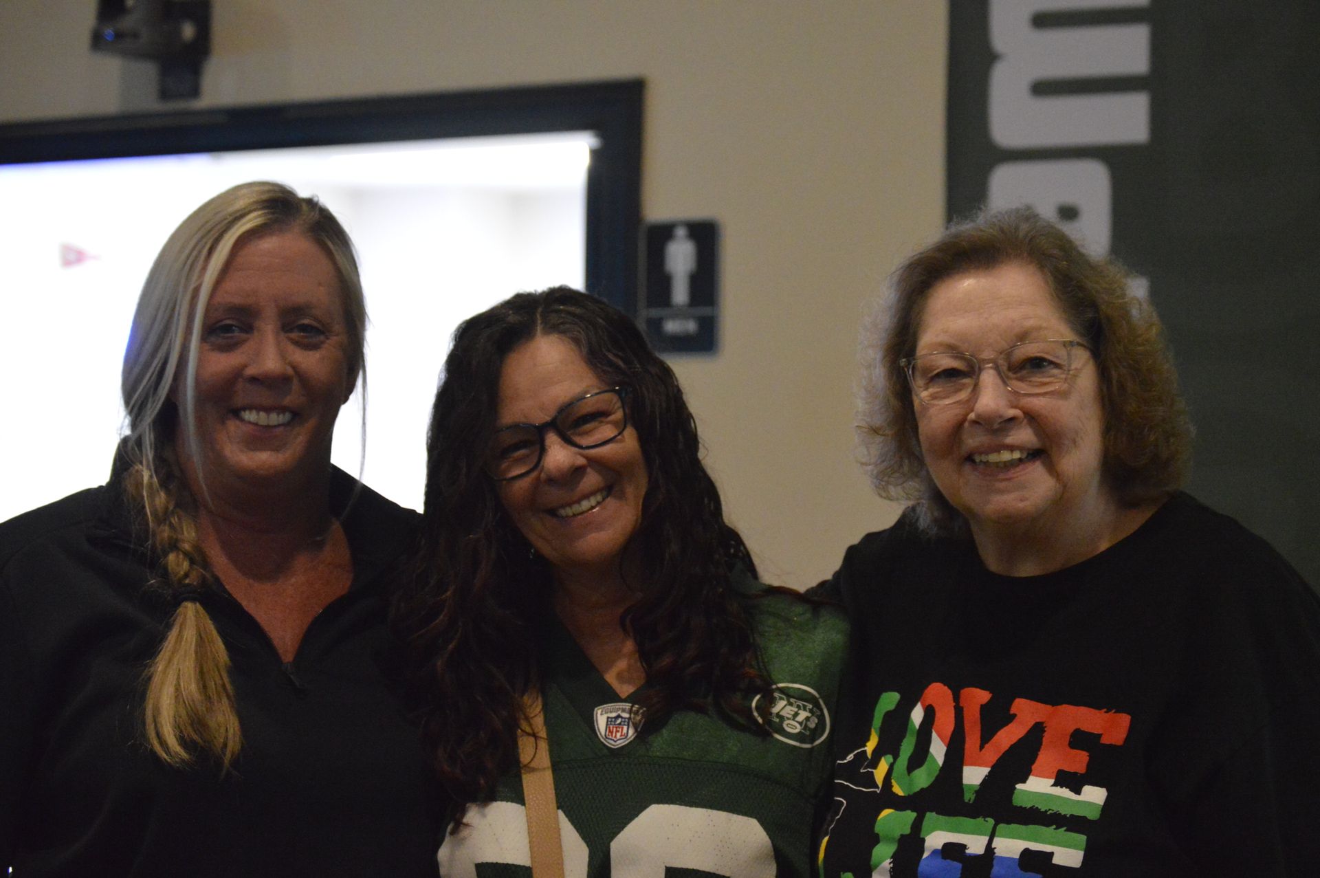 A group of people are sitting at tables in front of a large screen.