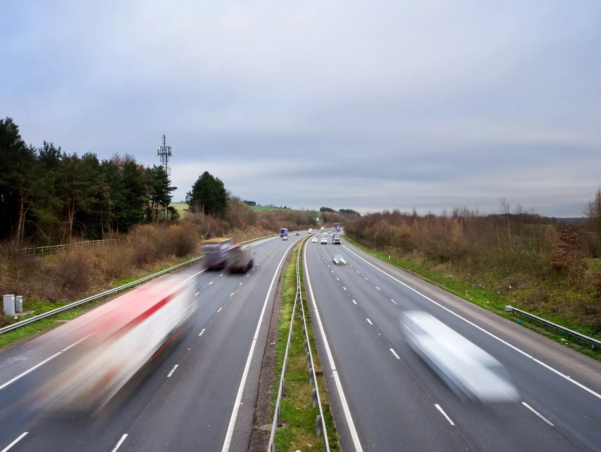 Highway with blurred vehicles under a cloudy sky.