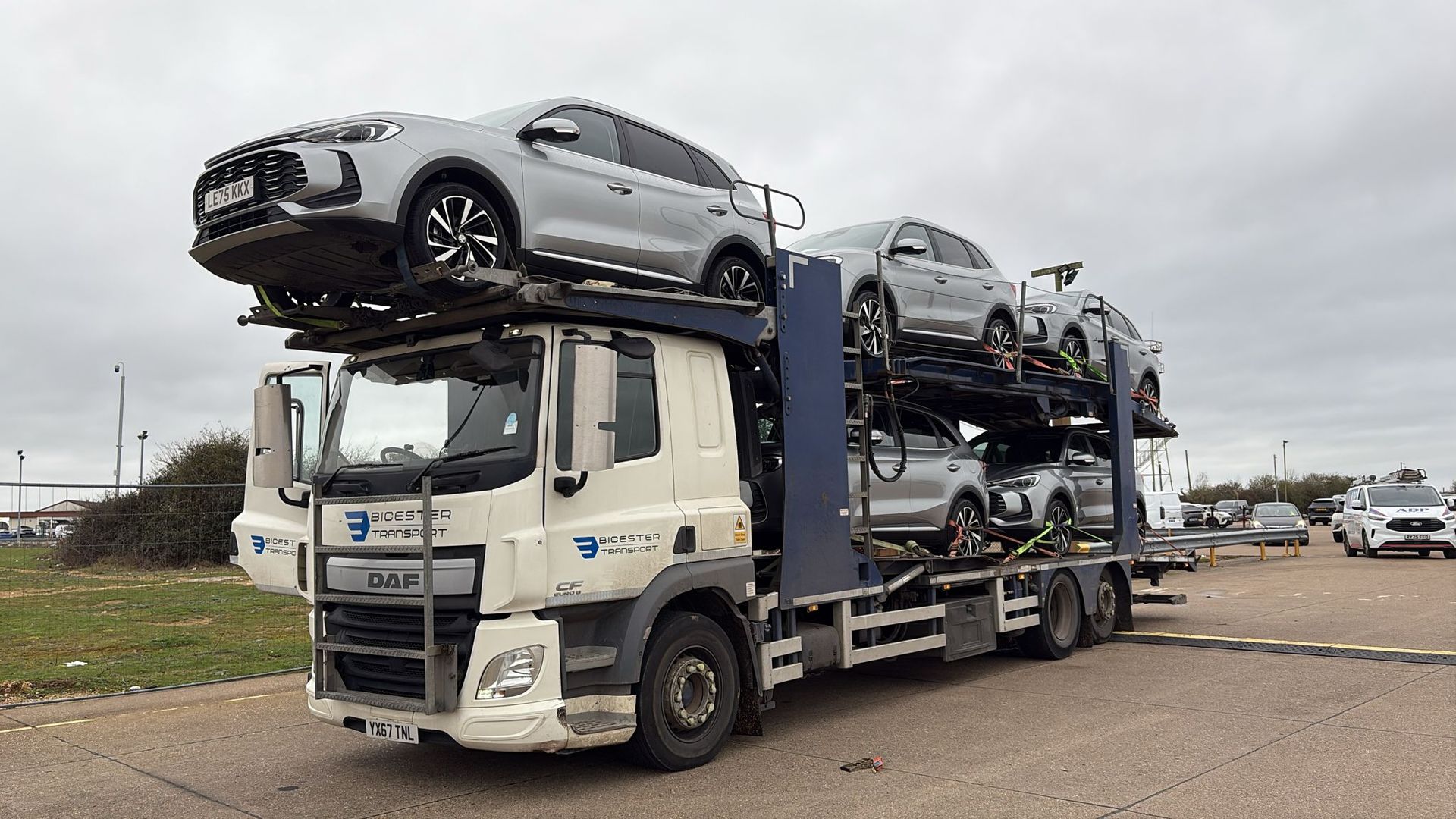 Car transporter truck carrying two cars on a residential street.
