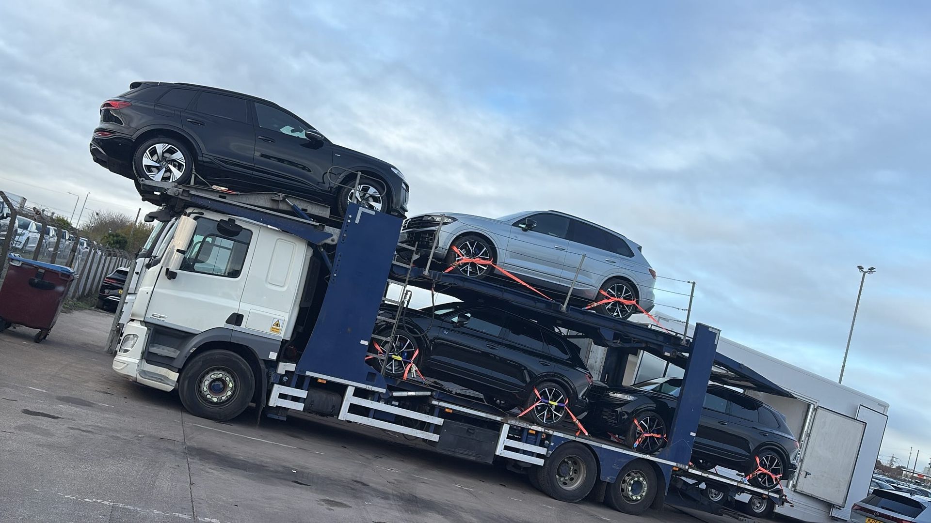 Car transporter truck carrying several dark-colored SUVs.
