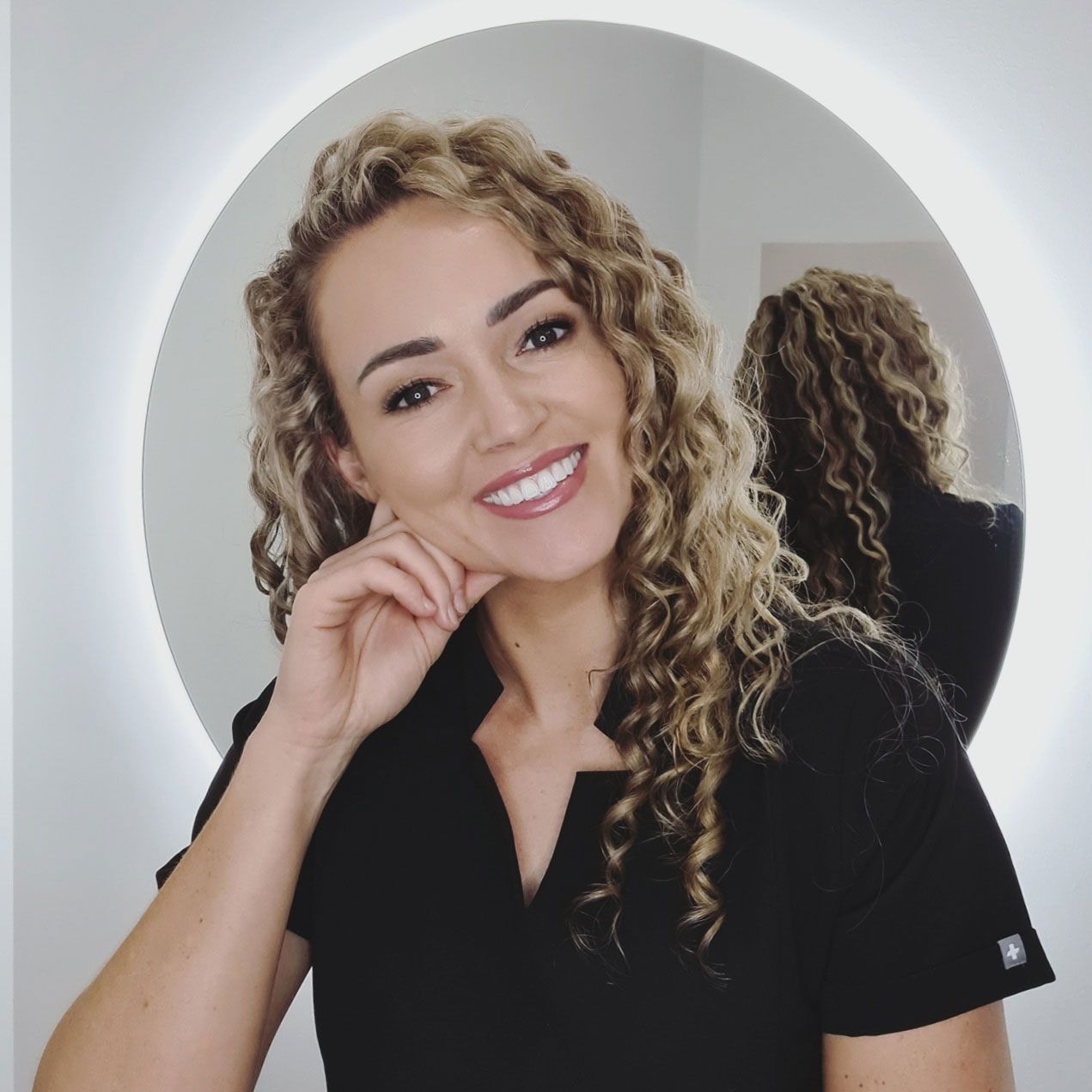 A woman in a gray scrub top is holding a white device in her hand. — Nurose Aesthetics in Nundah, QLD