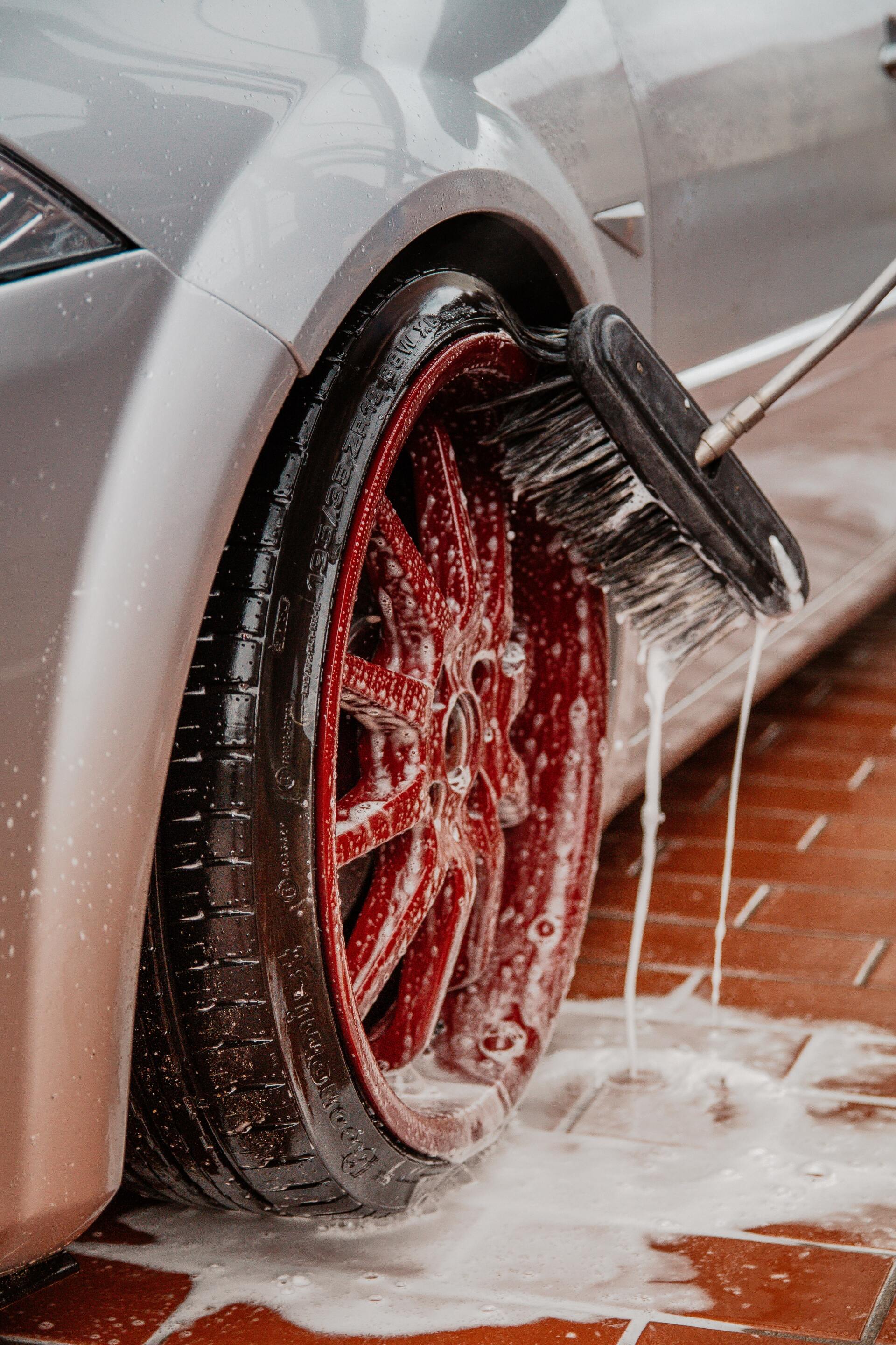 red alloy wheel being washed with a brush
